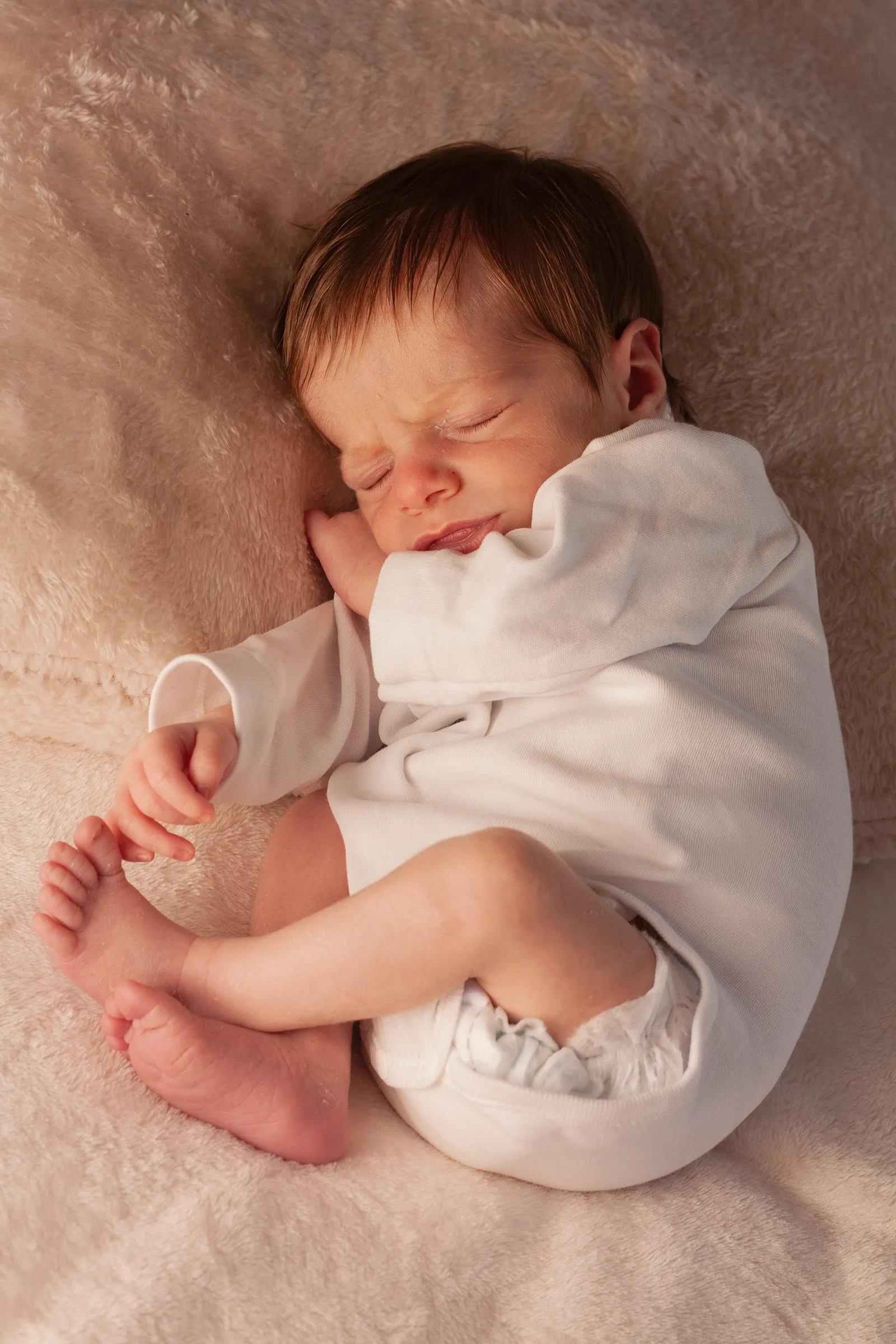 Recién nacido dormido acurrucado entre las manos de sus padres